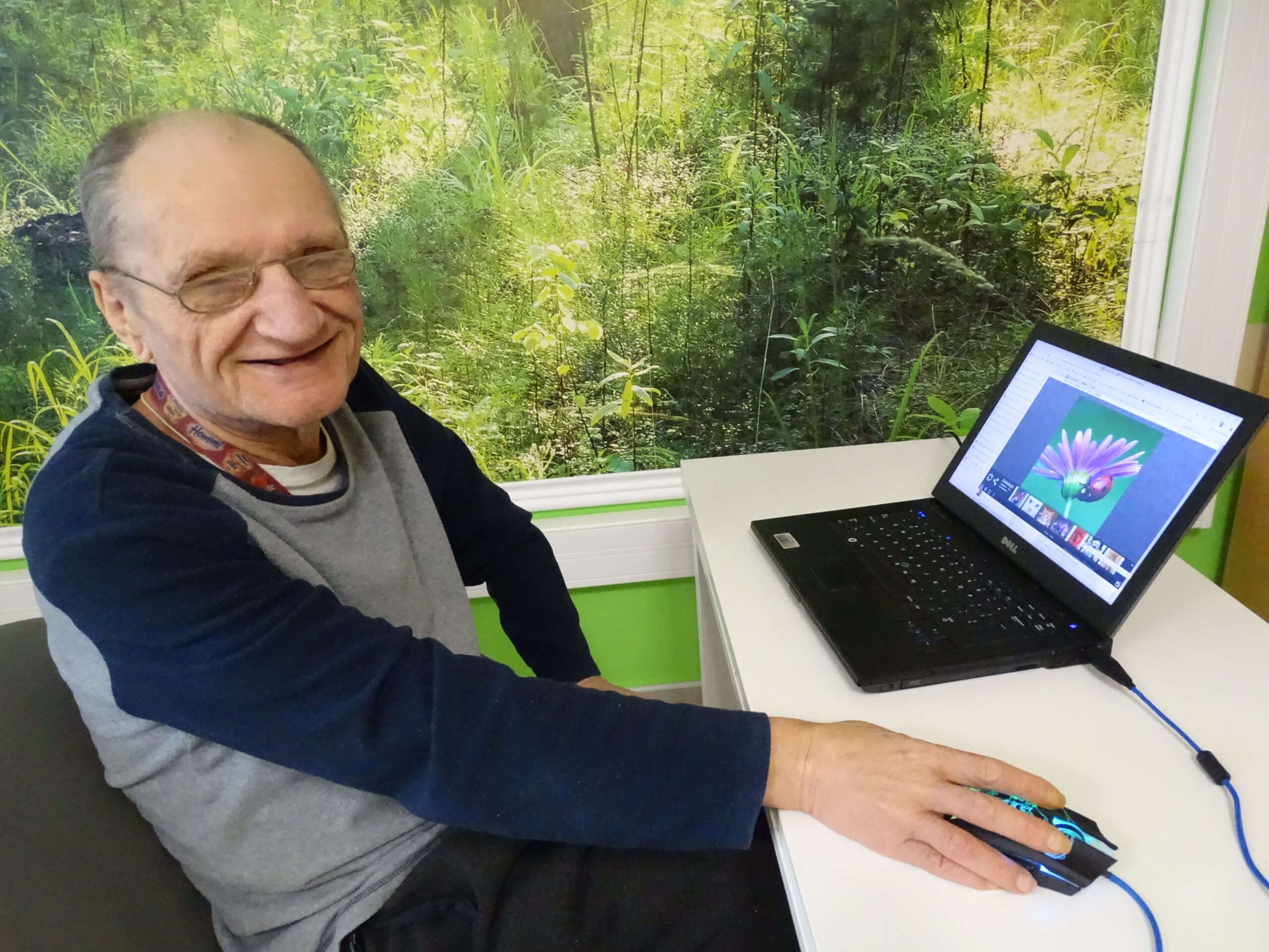 Uśmiechnięty starszy mężczyzna biorący udział w warsztatach komputerowych