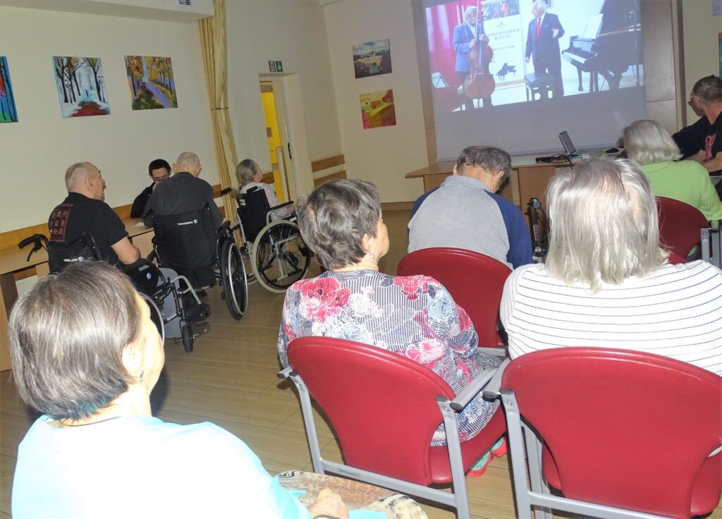 Seniorzy glądają film wyświetlany na ekranie projekcyjnym